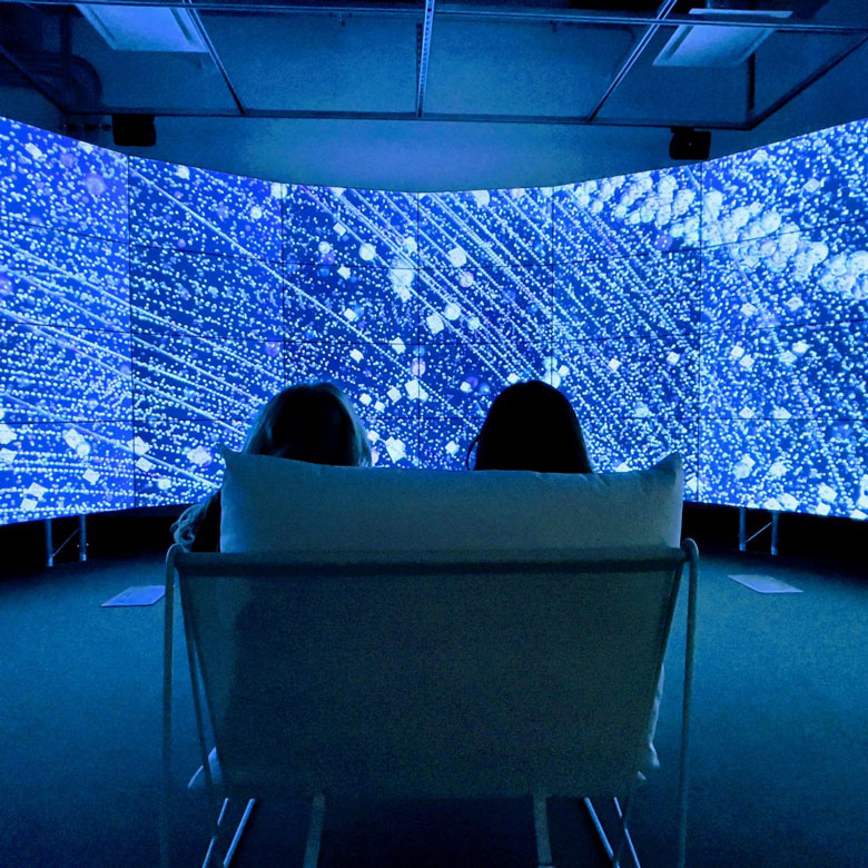 Students sitting in front of the All the Stars We Cannot See exhibit